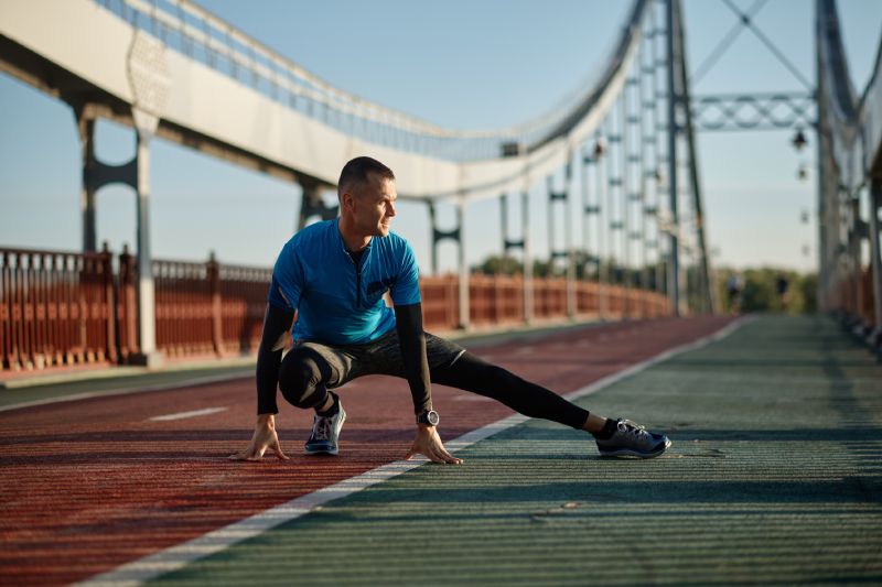 Atleta de mediana edad haciendo ejercicio de calentamiento antes de empezar a correr