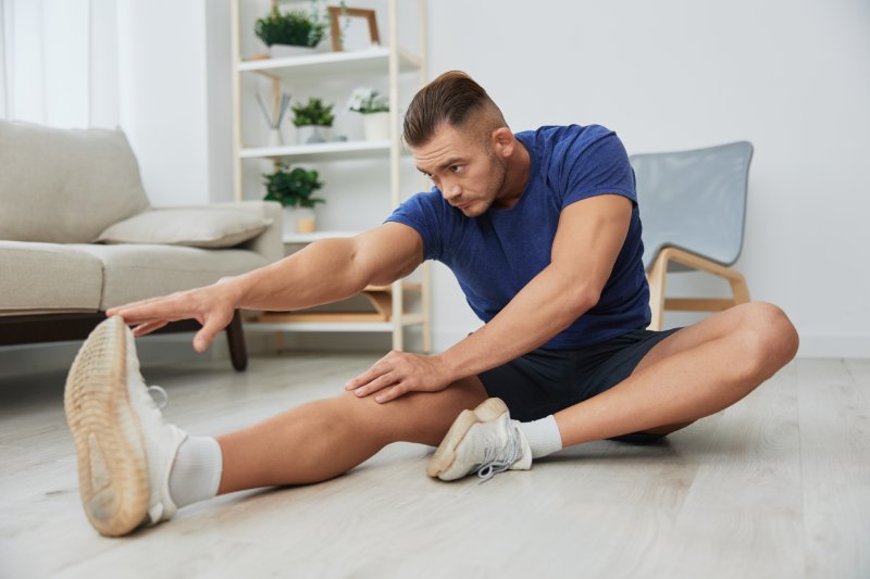 Hombre deportista entrenando en casa, ejercicios de estiramiento para músculos de brazos, piernas y espalda, cuerpo fuerte y postura correcta, el concepto de salud y belleza