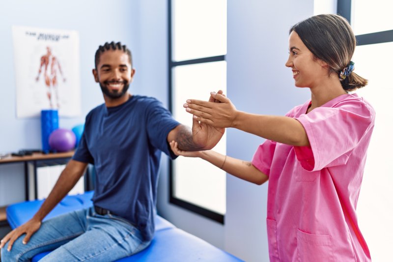 Hombre y mujer con uniforme de fisioterapeuta con sesión de rehabilitación estirando el brazo en la clínica de fisioterapia